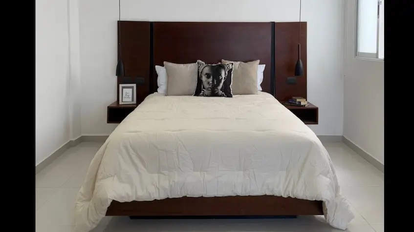 A bed with a headboard and a pillow in Zentrik Tulum Estudios