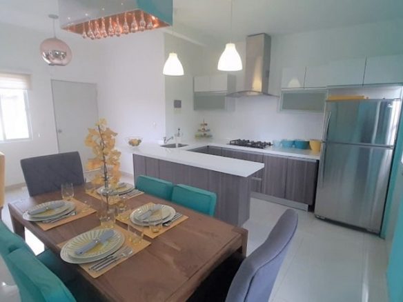 Cocina con comedor con sillas grises y verdes en Palmyra Condos