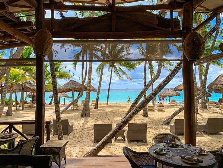 Club de playa con palmeras, palapas y camastros en la Riviera Maya