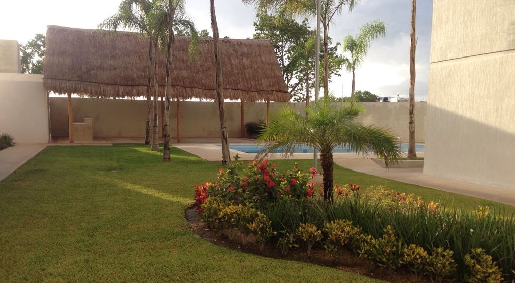 Jardín y parrilla bajo palapa junto a la piscina en Los Olivos