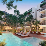 Deux piscines et une terrasse en bois au milieu, entourées d'un immeuble résidentiel blanc à Costa Caribe.
