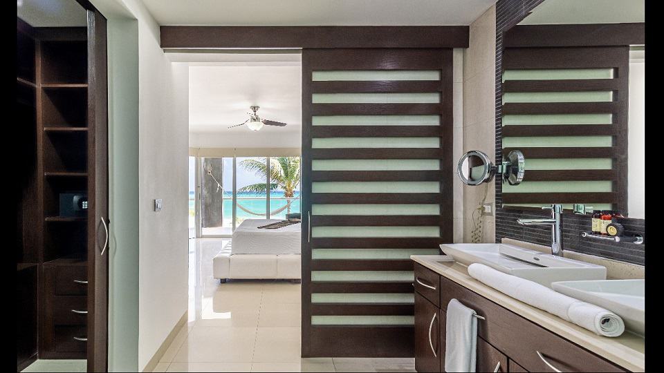 Baño con lavabo doble y dormitorio con vista al mar en Mareazul Beachfront Residences