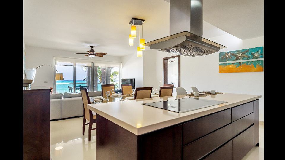 Isla de cocina con campana y mesa de comedor en Mareazul Beachfront Residences