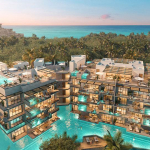 Vista de torres residenciales iluminadas con complejo de piscinas y vista al mar en Eos Tulum