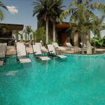 Une piscine avec quatre chaises longues dans l'eau entourée de végétation à Menesse Midtown 2