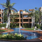 Piscine principale entourée de palmiers et d'un bâtiment résidentiel en forme de U à Aak Residencial Tulum