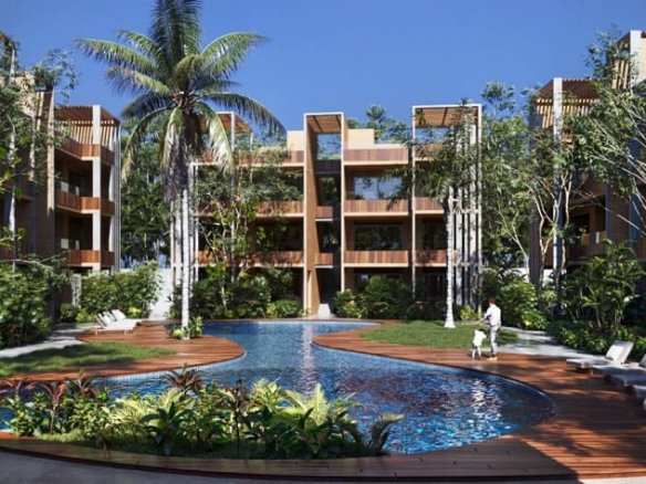 Main pool surrounded by palm trees and a U-shaped residential building at Aak Residencial Tulum