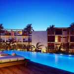 Piscina sky pool largo con algunas hamacas en la noche en The Waves Tulum
