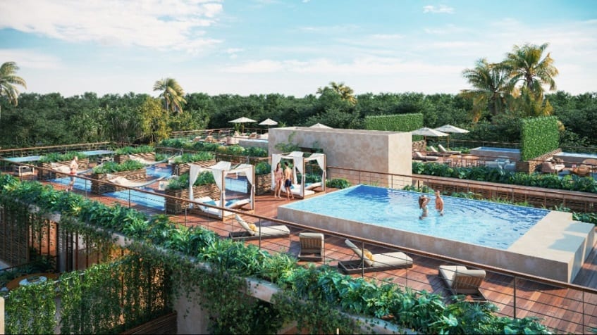 Alberca común en la azotea y una pareja dentro de ella y otra parada en Amelia Tulum