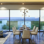 Studio condo interior with glass wall corner, sofa, and large dining table in Musa del Carmen