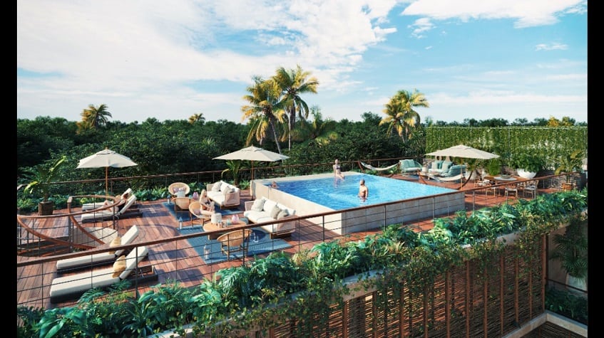 Vista de la azotea con piscina, solárium y gente merodeando en Amelia Tulum