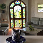 Sala con puerta de cristal de colores y sofá esquinero grande de Casa Playacar