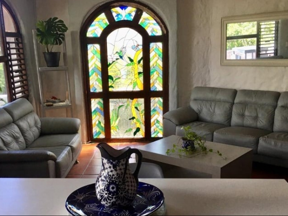 Sala con puerta de cristal de colores y sofá esquinero grande de Casa Playacar