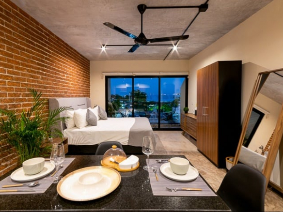 Estudio con decoración de paredes de ladrillo y cama king en Believe Playa Condos