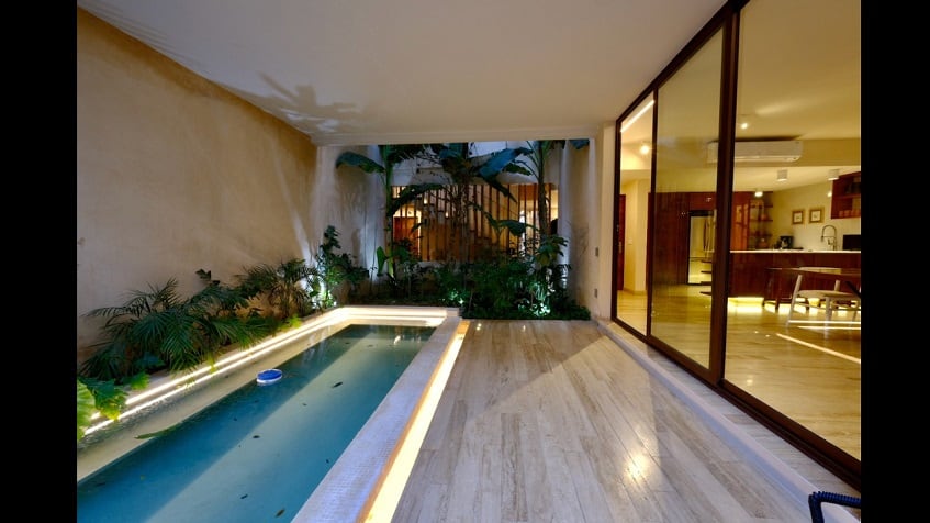 Terraza con piscina larga por ventana de puerta corredera, rodeada de vegetación en Casa Libre Airena