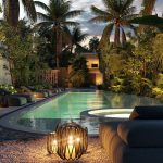 Vista nocturna del área de la piscina rodeada de vegetación en Reserva Lux Tulum