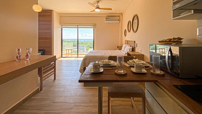 Interior de estudio con una pequeña cocina y una cama en Areia Playa del Carmen