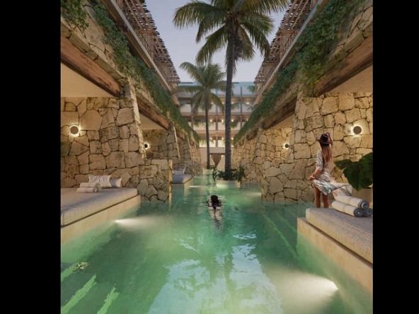Piscina larga entre terrazas privadas divididas por paredes y gente relajándose en Alquimia Home Resort