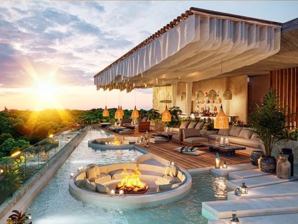 Piscina con áreas circulares para sentarse con fogata y bar durante un atardecer en Nequen Tulum
