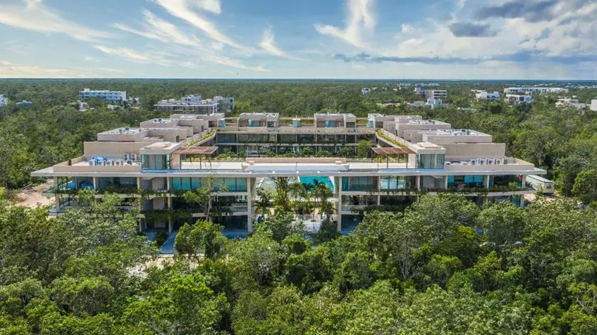 Vista aerea de un edificio de departamentos con arboles alrededor en Mistiq Premium Tulum