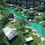 Jardín con un río entre dos edificios residenciales y camas de la playa en el distrito de Amira