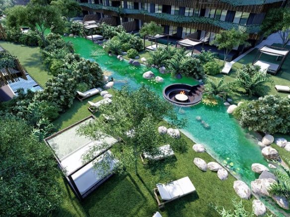 Jardín con un río entre dos edificios residenciales y camas de la playa en el distrito de Amira