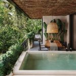 Terraza con una pequeña alberca junto a la gran mesa rodeada de vegetación en Talulah Tulum