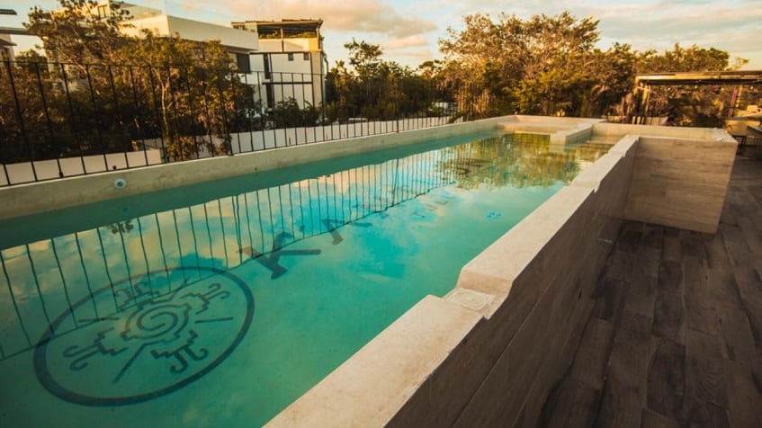 Piscina larga junto a una valla rodeada de vegetación en Kantuun Tulum