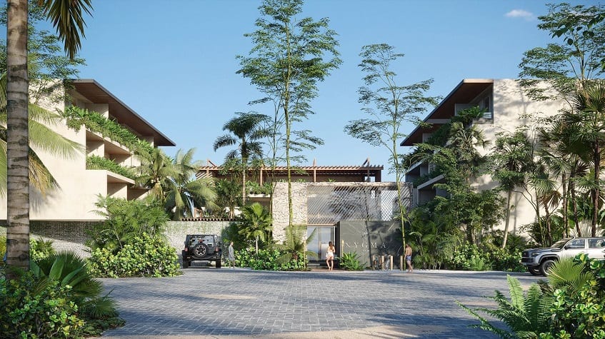 Fachada de edificio residencial rodeado de vegetación y estacionamiento en Nygma Tulum