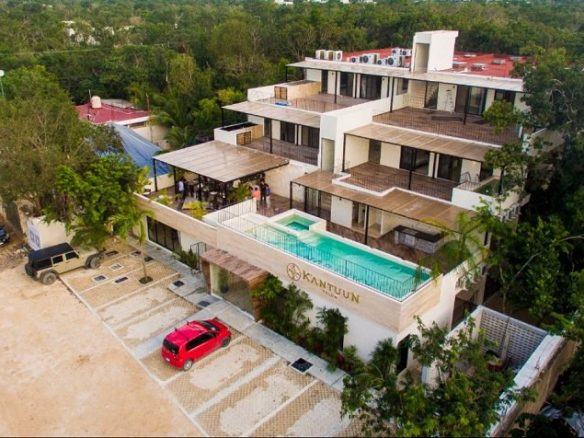 Edificio residencial con tres niveles de terrazas rodeado de vegetación en Kantuun Tulum