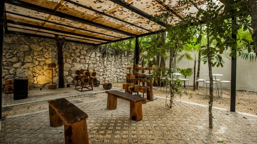 Gimnasio al aire libre con pesas y asientos de madera en Kantuun Tulum
