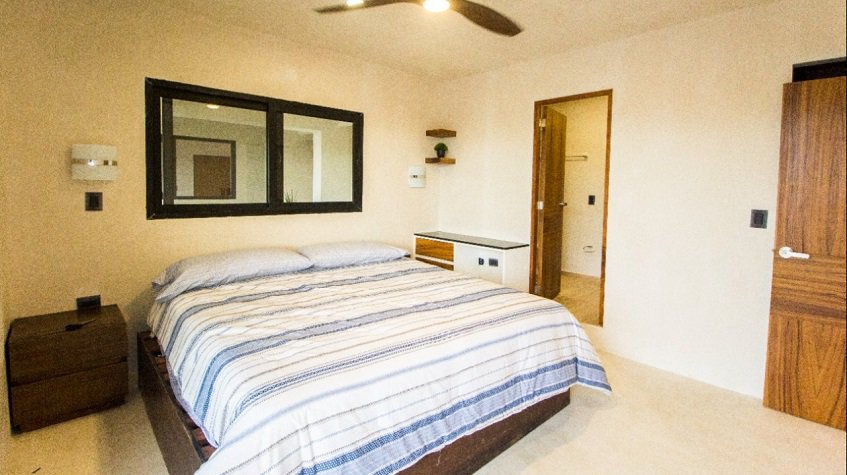 Dormitorio principal con cama king size, puerta abierta al baño en Kantuun Tulum
