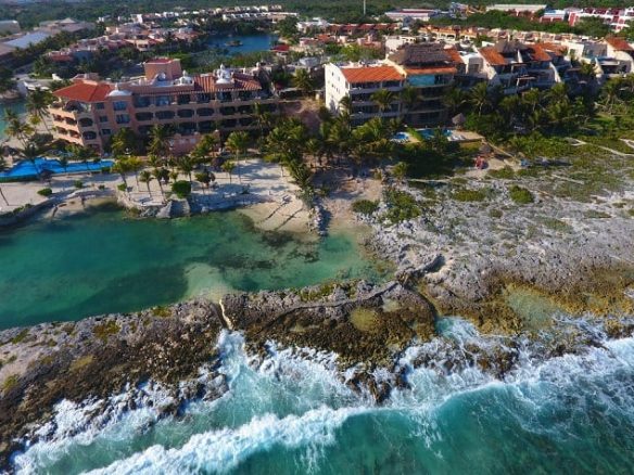 Vista superior de los edificios costeros y el mar con las rocas en Casacun Puerto Aventuras