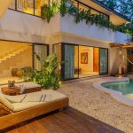 Terraza de la piscina rodeada de vegetación y hamaca sobre el agua en La Privada Tulum