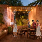 Terraza y tres mujeres y un hombre junto a una parrilla, mesa de comedor, sillas, vegetación en Tulix Tulum