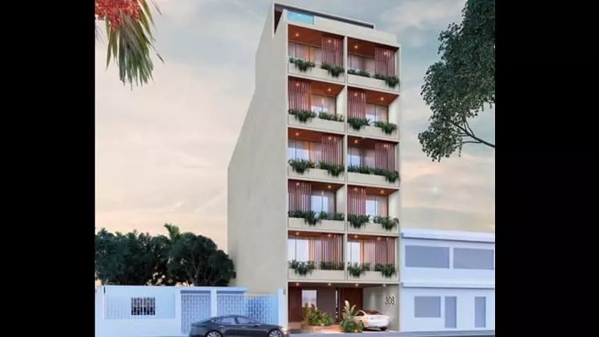 Fachada de edificio residencial con balcones verdes y autos que pasan por la calle en Veinte Playa Boutique