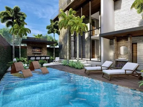 Ground-floor pool surrounded by a fence and green area, bar, and solarium at Soul Living Tulum