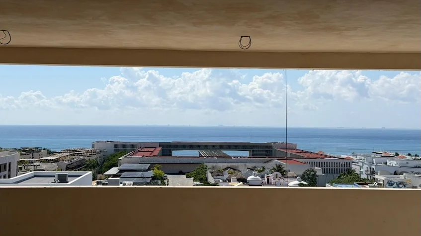 Vista panorámica desde un balcón superior que muestra edificios urbanos, la costa y el mar Caribe, perteneciente al desarrollo Distrito Playa
