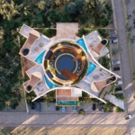 Vue aérienne d'un immeuble résidentiel rond à côté d'une jungle, piscine ronde au milieu, terrasses de piscine sur le toit à Oniric Tulum