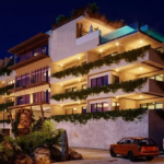 Una fachada exterior de un edificio en la noche con autos estacionados afuera en Hunab Ku Tulum