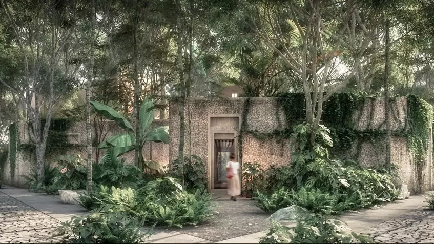 Una mujer caminando hacia una puerta y arboles alrededor en Candela Tulum