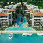 Piscina en planta baja en forma de río entre edificios residenciales con amplias terrazas y embarcadero en Puerto Aqua Puerto Aventuras