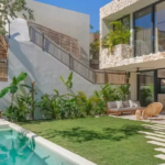 A terrace with a garden, a pool, and a rear facade of the house in Villa Eterea Tulum
