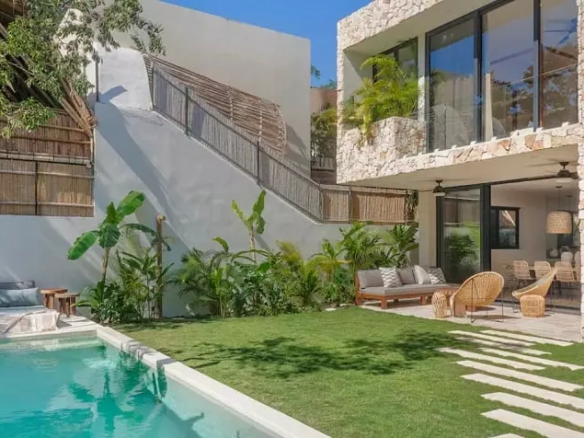 Una terraza con jardin, una alberca y una fachada trasera de la casa en Villa Eterea Tulum
