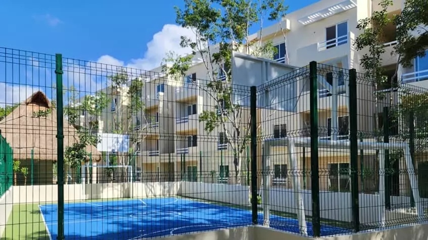 A basketball court and soccer field with a palapa in the background at La Selva Residences