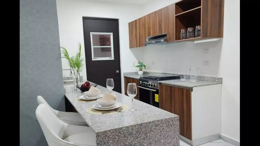 Kitchen with wood finishes, granite countertops and stove in La Selva Residences