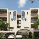 Fachada de edificio con arboles alrededor y estacionamiento con autos en Elenia Tulum
