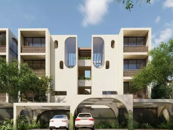 Building facade with trees surrounding and parking with cars in Elenia Tulum