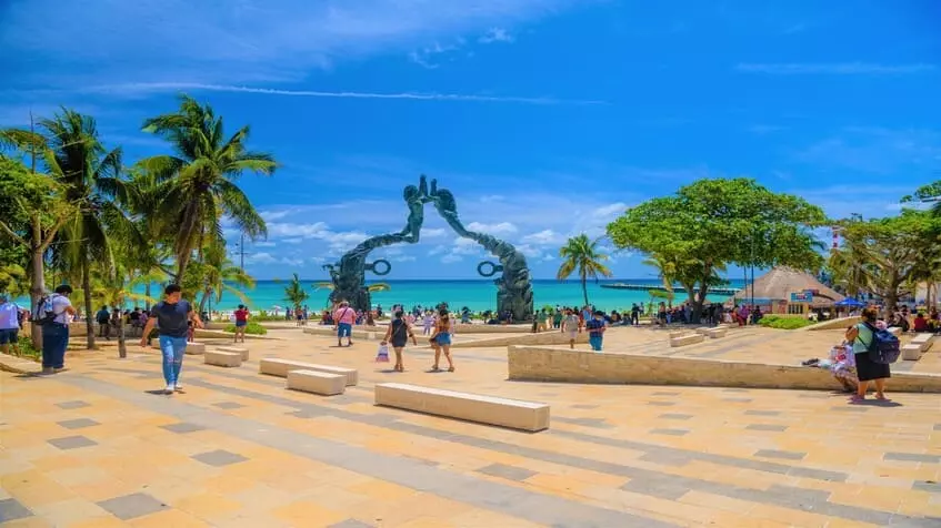 Un mirador con una estatua y personas caminando en Playa del Carmen