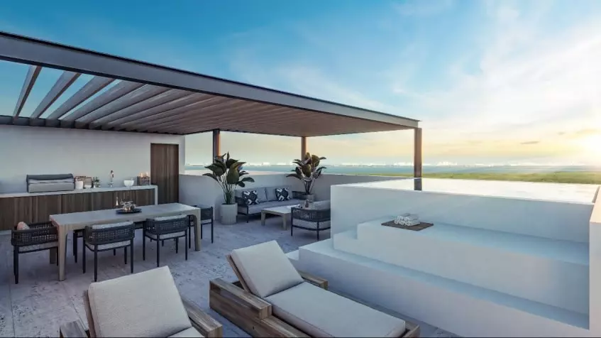 Una terraza con una mesa y camastros con vista al mar en Le Parc Cancun